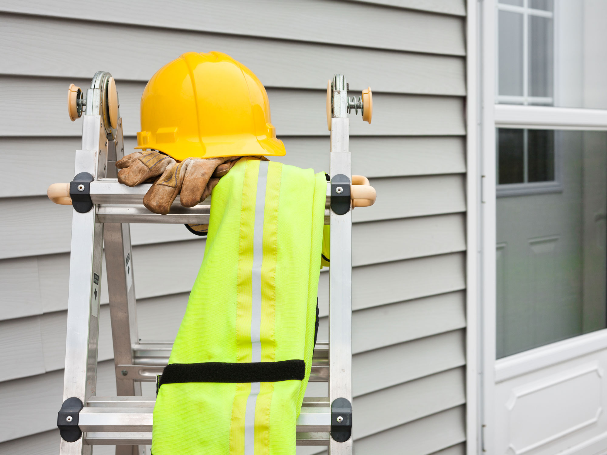 ladder outside house with a hard hat 